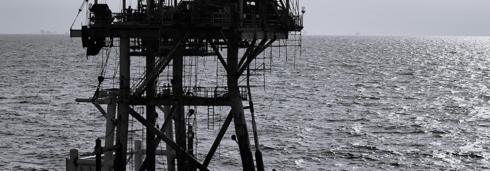 Oil rig surrounded by ocean in black and white