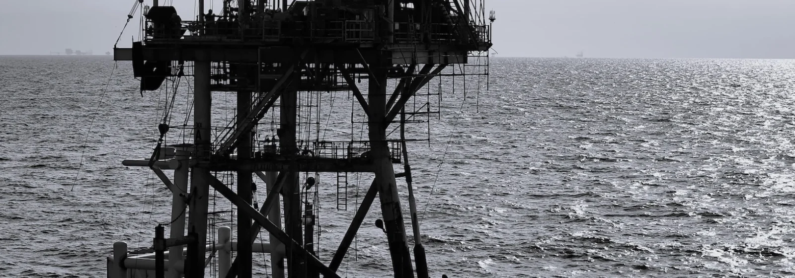 Oil rig surrounded by ocean in black and white