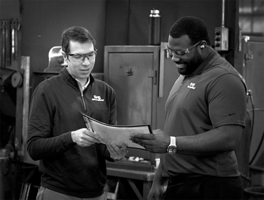 Two Strong Hold team members in PPE smiling and reviewing a document